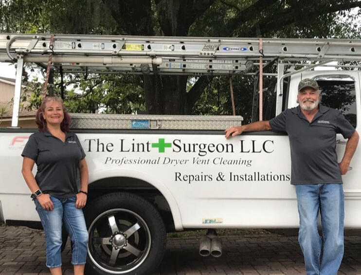 Claudia and Scott Rosenfeld standing in front of their truck with the company name " The Lint Surgeon LLC" written on the side